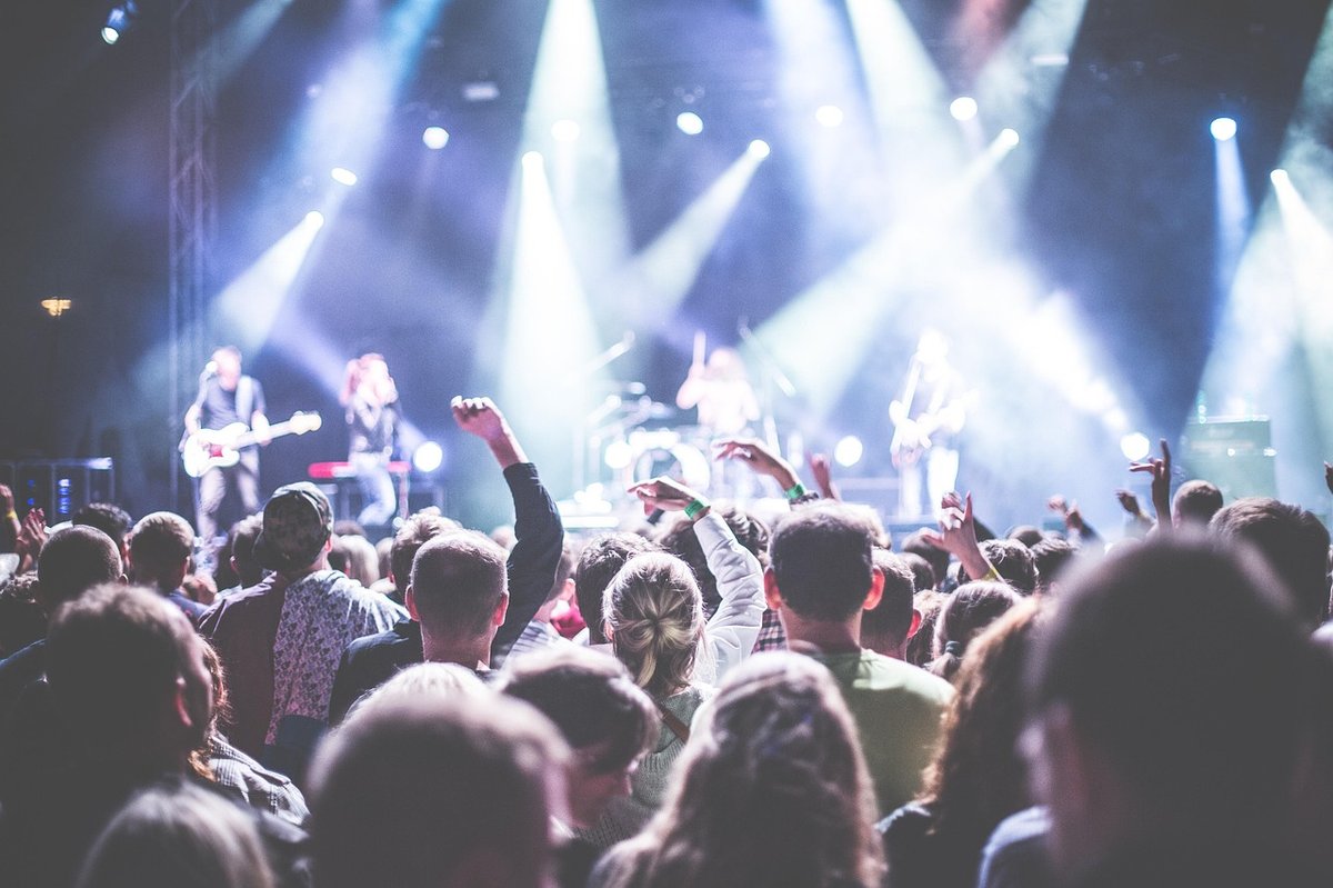 Crowd facing a stage lit by spotlights while a band performs